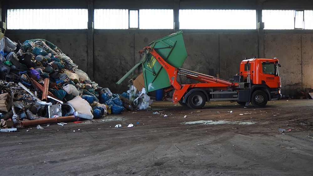 Ein Müllberg auf den weiterer Müll geladen wird über einen roten LKW.