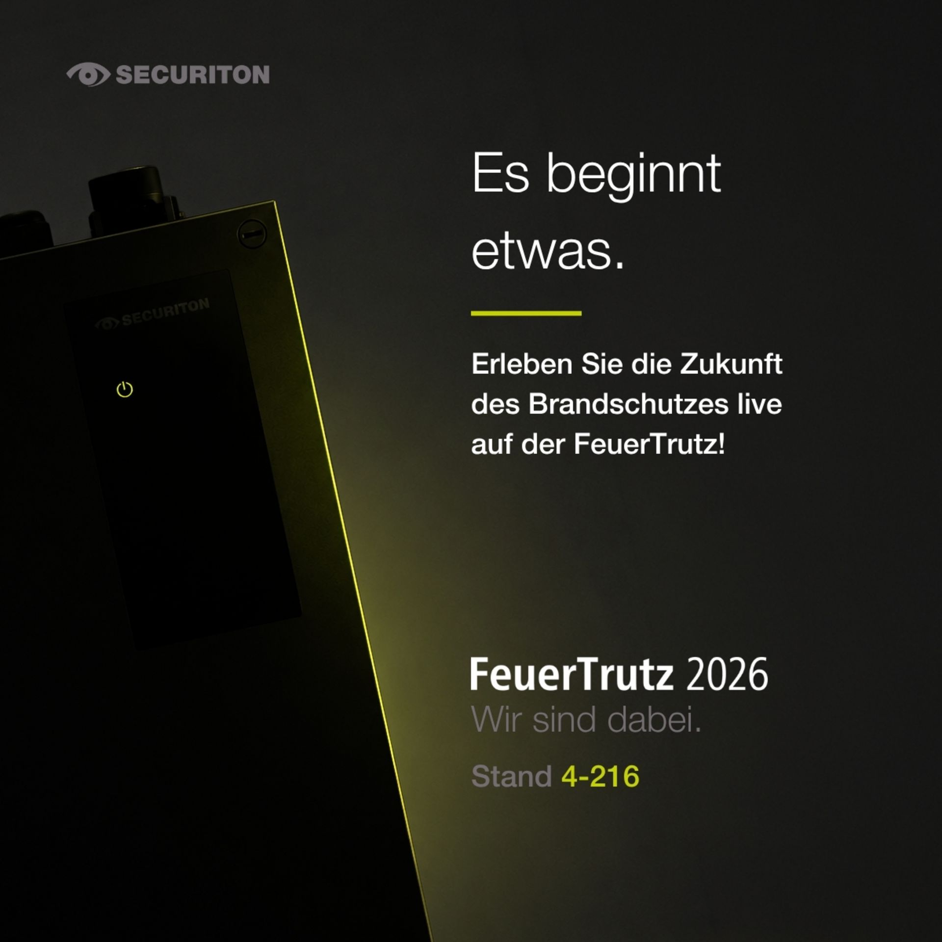 Dunkles Werbemotiv von Securiton mit einem beleuchteten technischen Gerät im Vordergrund. Rechts steht der Text "Es beginnt etwas. Erleben Sie die Zukunft des Brandschutzes live auf der FeuerTrutz!" sowie der Hinweis "FeuerTrutz 2026 - Wir sind dabei. Stand 4-216".
