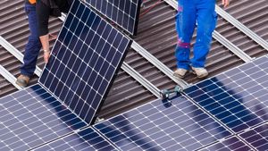 Eine Solaranlage wird von zwei Personen auf einem Dach montiert.