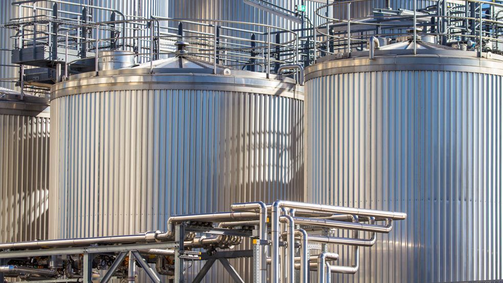 Große industrielle Edelstahltanks und Rohrleitungen in einer modernen Produktionsanlage.