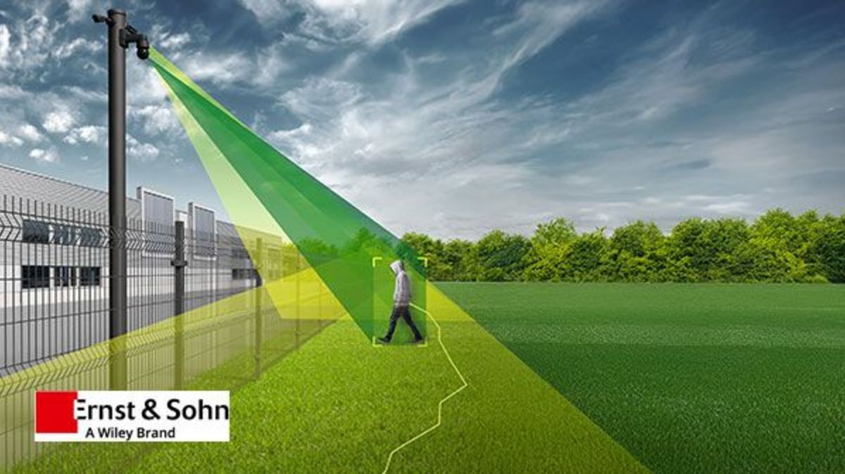 Ein Videosicherheitsystem zeigt einen Überwachungsstrahl, der eine Person auf einem offenen Gelände erfasst. Das Bild zeigt eine Überwachungskamera an einem Zaun, die in grünen und gelben Farben den Bereich abdeckt, der überwacht wird. Im Hintergrund sind Gebäude und ein grünes Feld zu sehen. Das Bild ist mit dem Logo von Ernst & Sohn versehen, einem Wiley-Brand.
